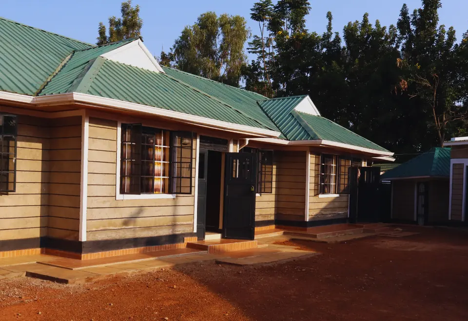 The compound in late-afternoon sun, with tall trees behind the homes