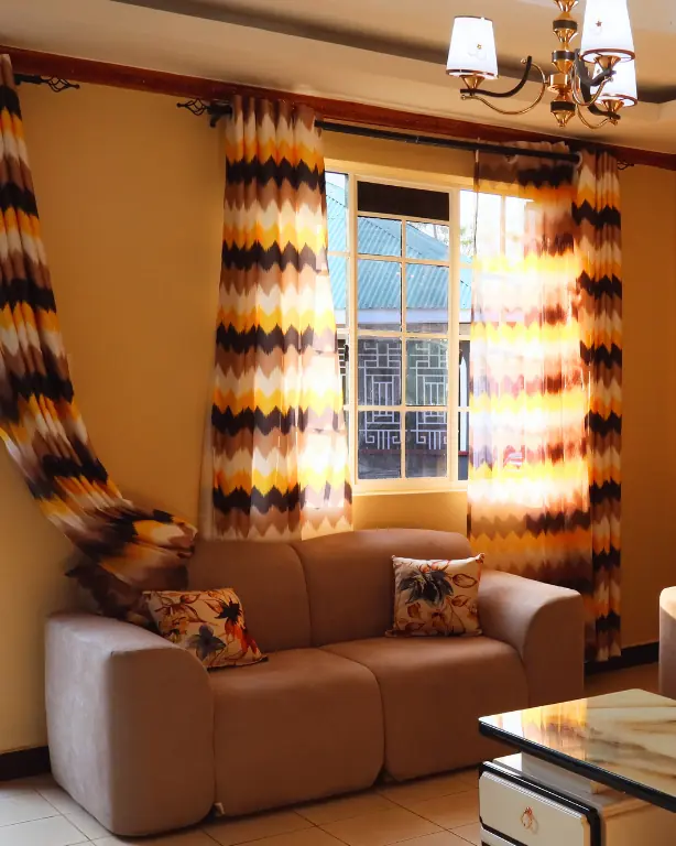Sitting room sofa by a sunlit window with patterned curtains